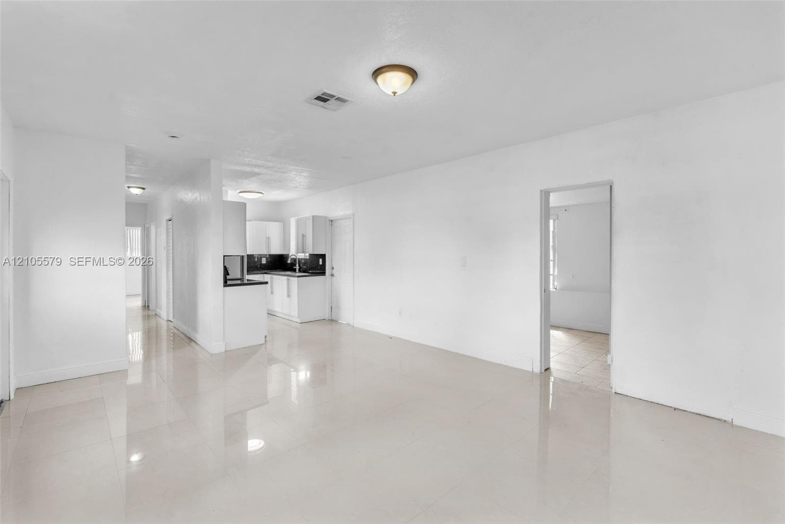 Interior space featuring neutral wall tones, large-format tile flooring, recessed and flush-mount ceiling lighting, and kitchen cabinetry with contrasting countertops
