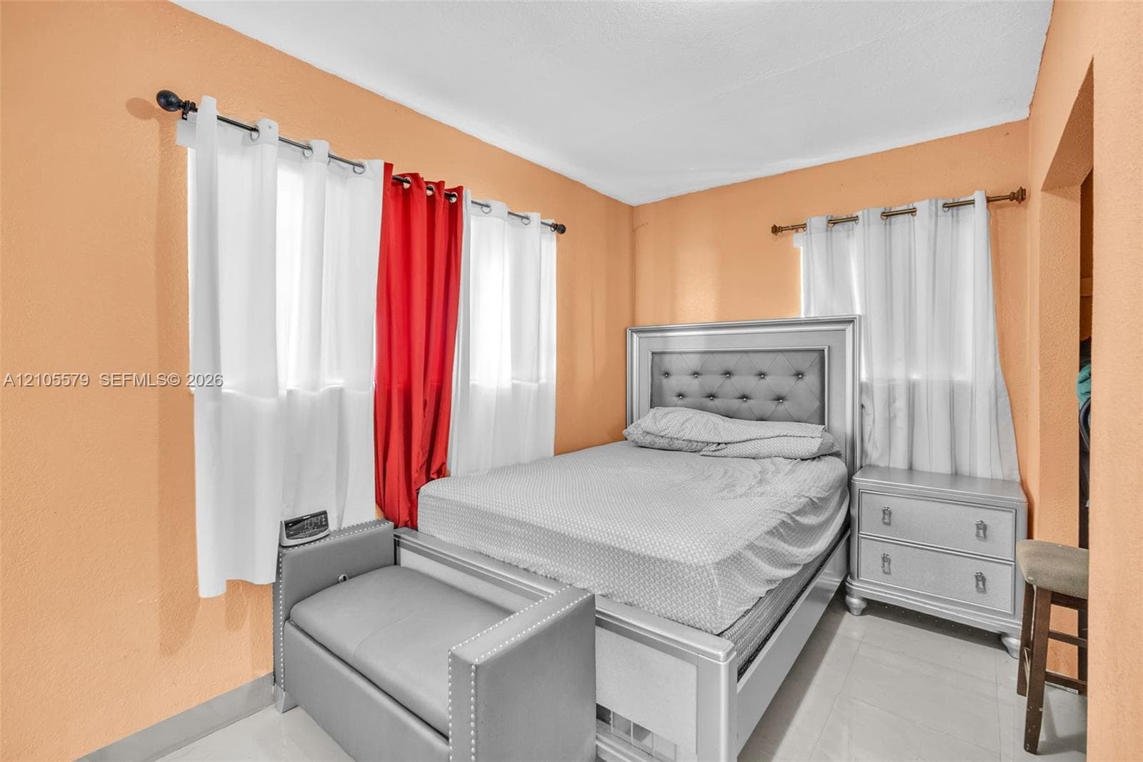 Bedroom with dual-aspect windows, white-finished rod hardware, and light-colored tile flooring