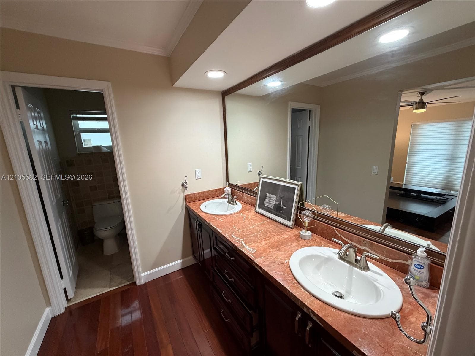 Double vanity with integrated sinks, rich wood-finish cabinetry, and recessed lighting