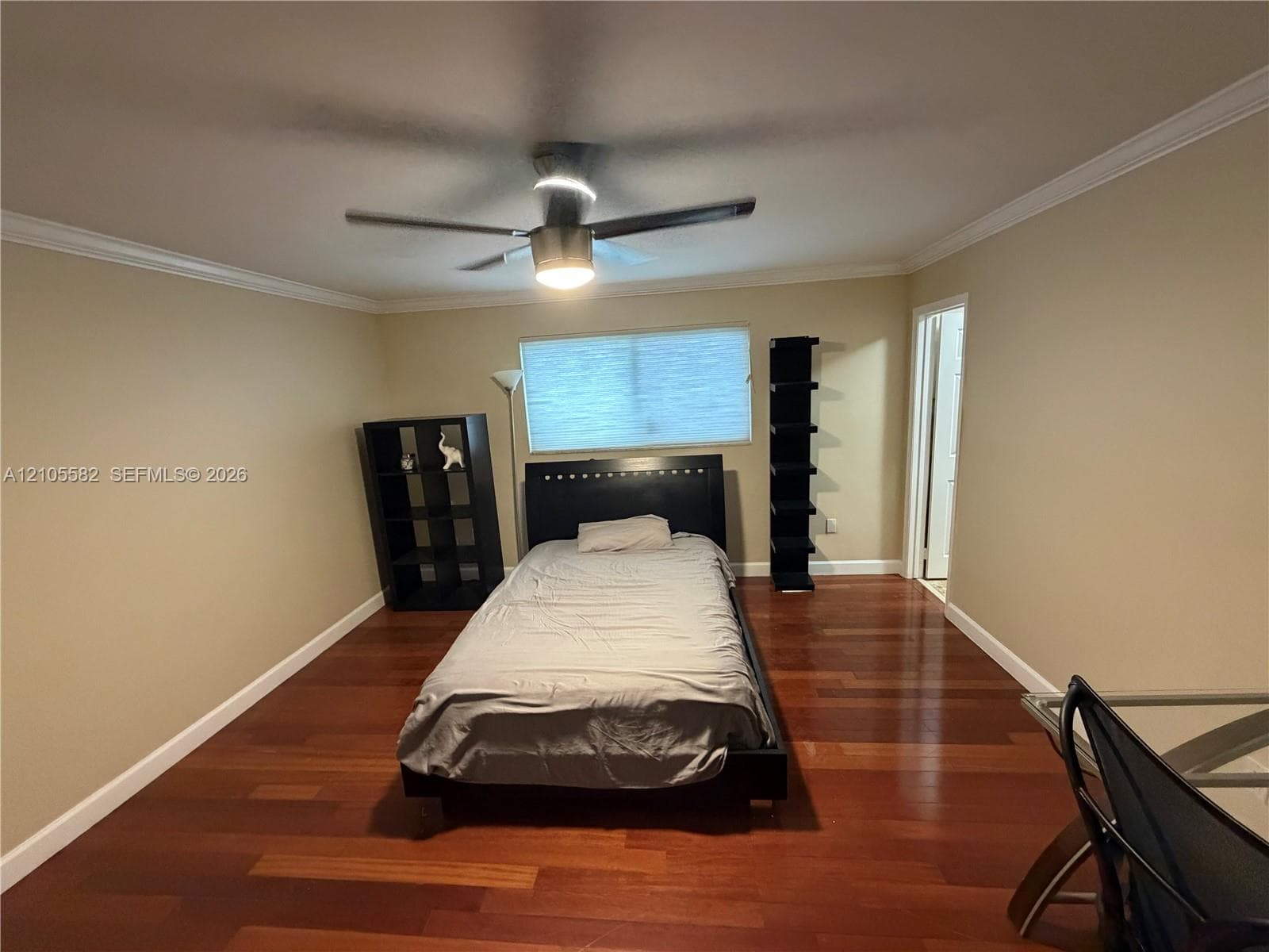 Wood-finish flooring throughout, crown molding, and a ceiling fan with integrated lighting