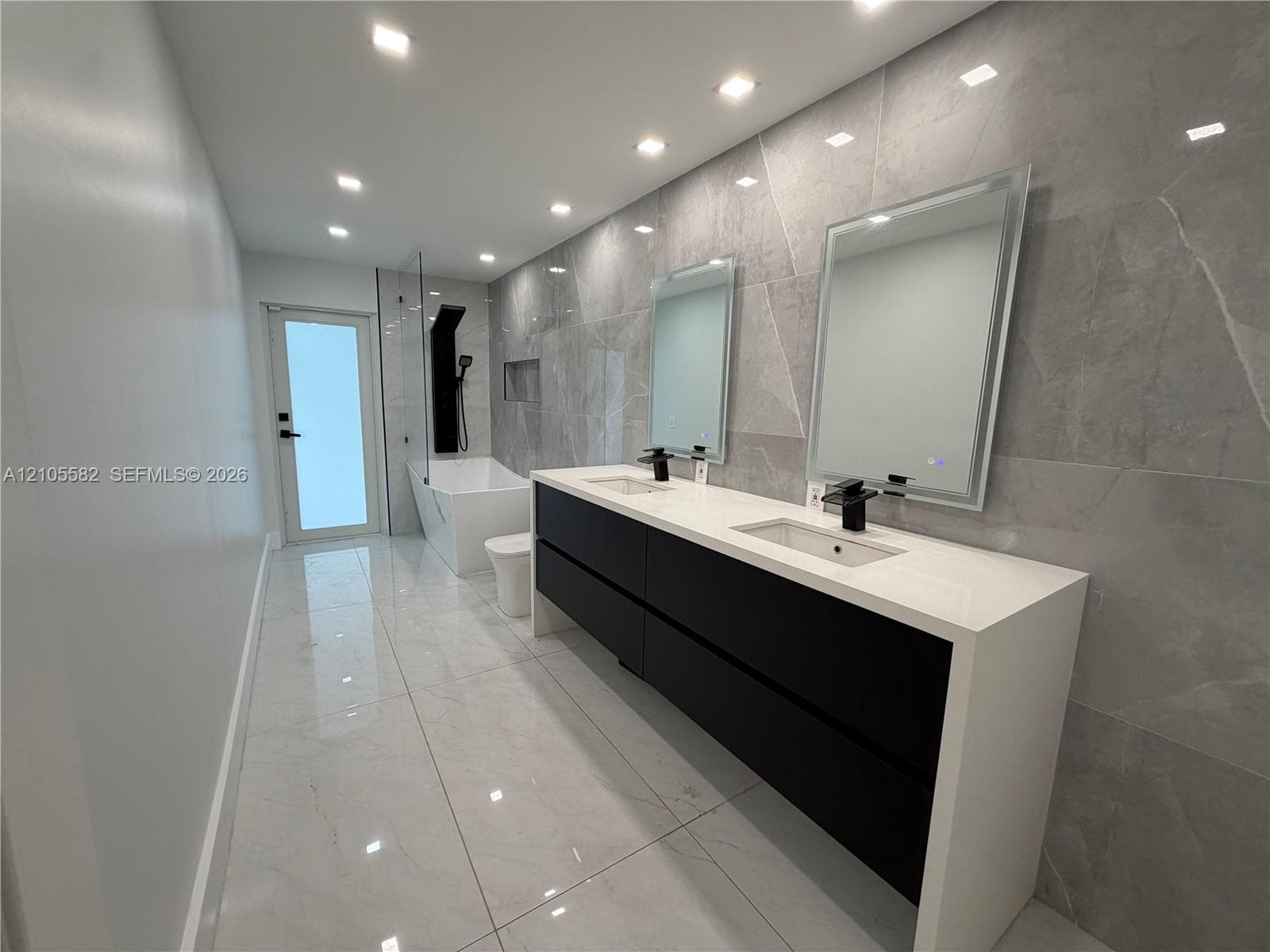 Dual vanity with waterfall countertop, matte black fixtures, integrated sinks, and mirrored medicine cabinets