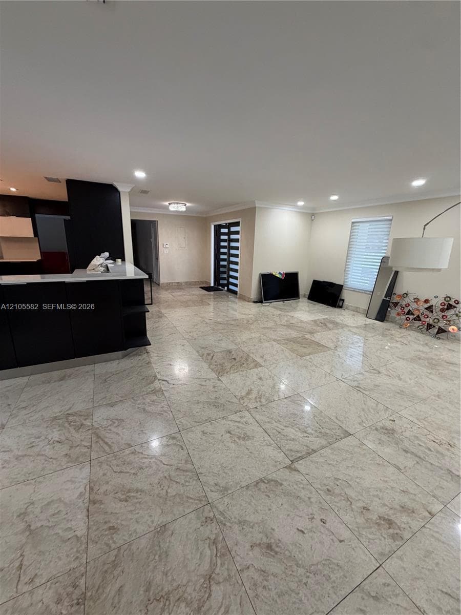Spacious open-concept interior featuring large format tile flooring, recessed ceiling lighting, and a contemporary entry door