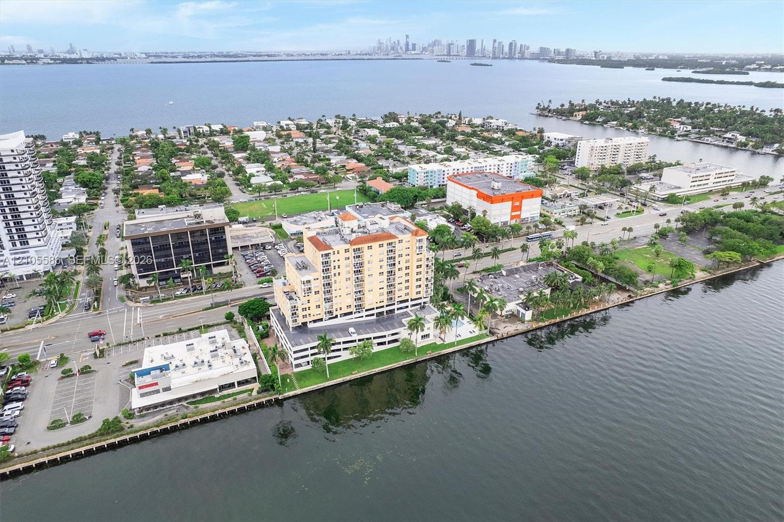 Waterfront property featuring multiple residential and commercial buildings, paved roads, and a distant city skyline