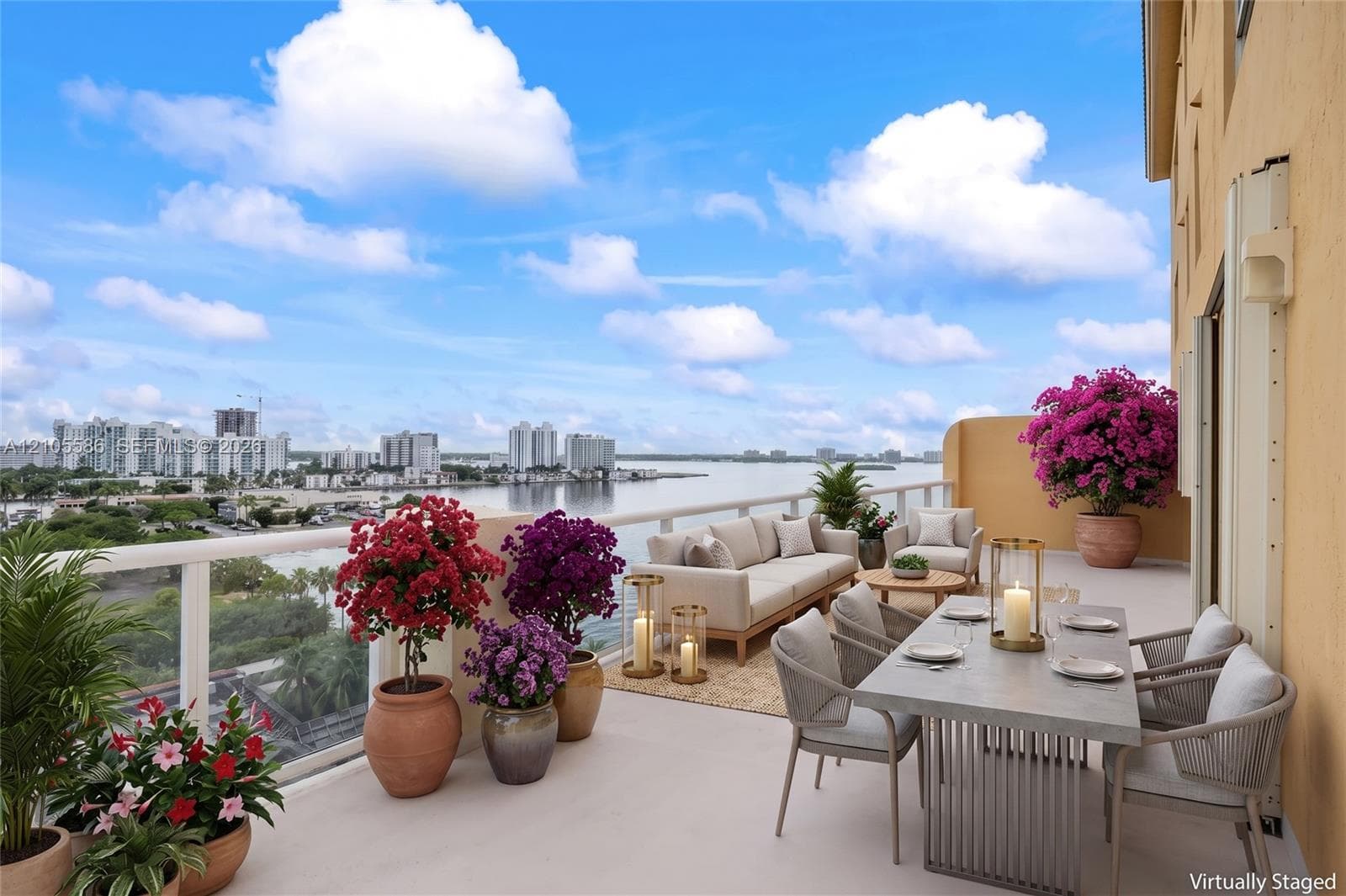 Expansive balcony with a glass railing, water backdrop, and distant cityscape
