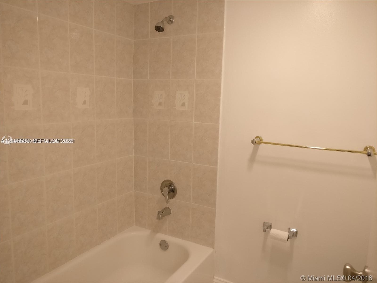 Bathtub with chrome fixtures, tiled shower surround, and a wall-mounted shower head