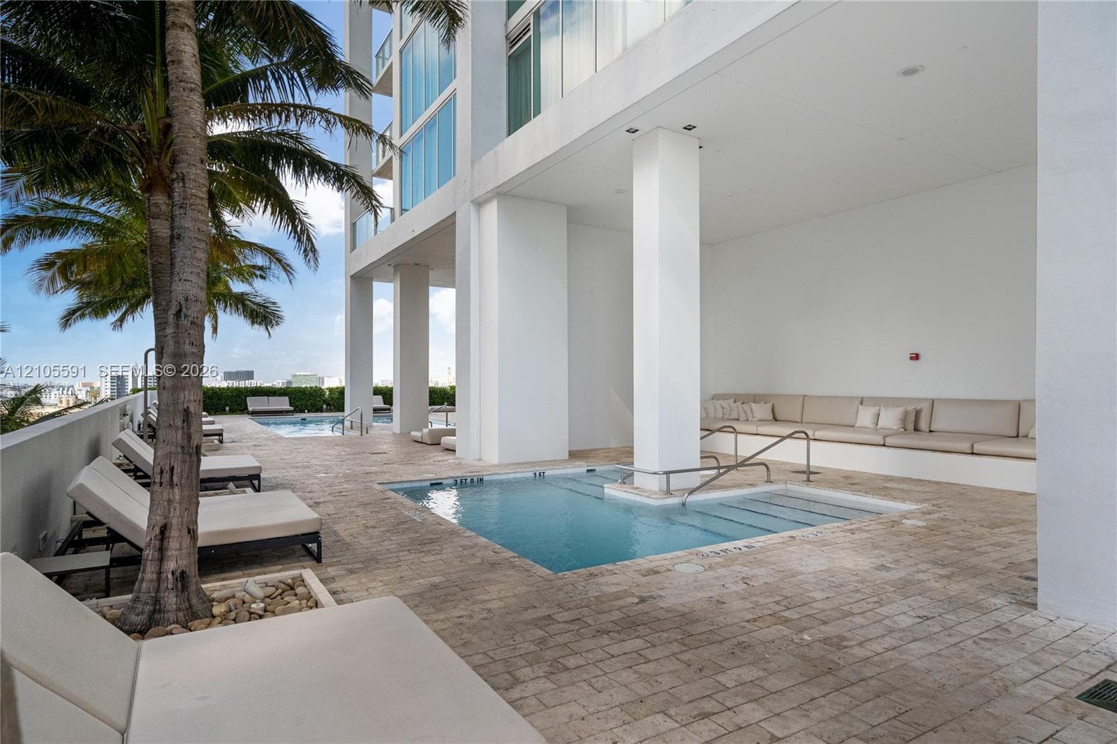 Outdoor aquatic feature with integrated steps, surrounded by stone paver decking and a built-in seating area