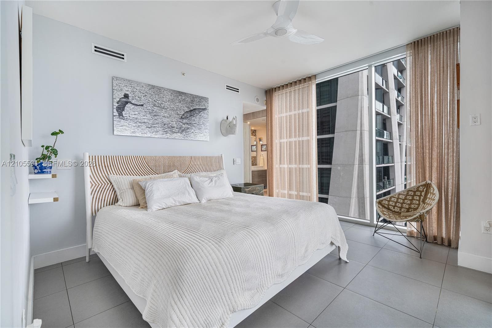 Full-height window with sheer and blackout drapery, ceiling fan, and tile flooring