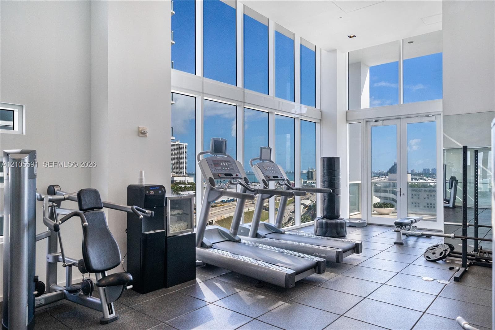 Gym space featuring floor-to-ceiling windows, tile flooring, and double glass doors