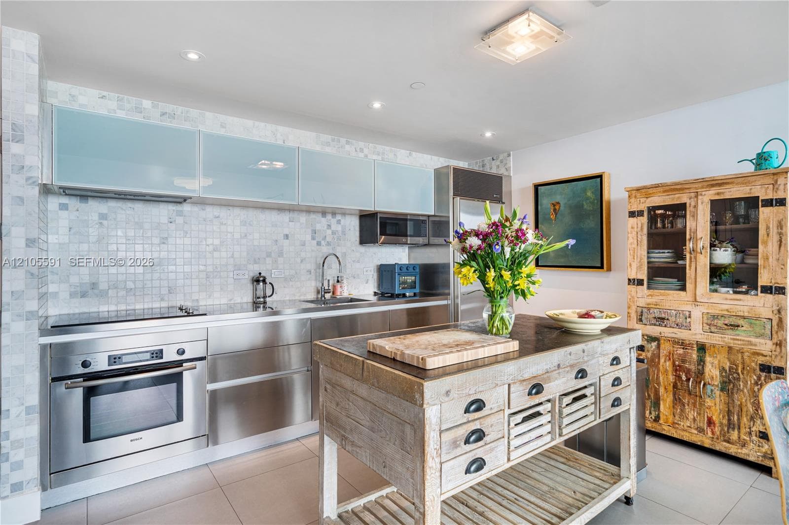 Stainless steel appliances, mosaic tile backsplash, recessed lighting, and a unique wood-finish kitchen island