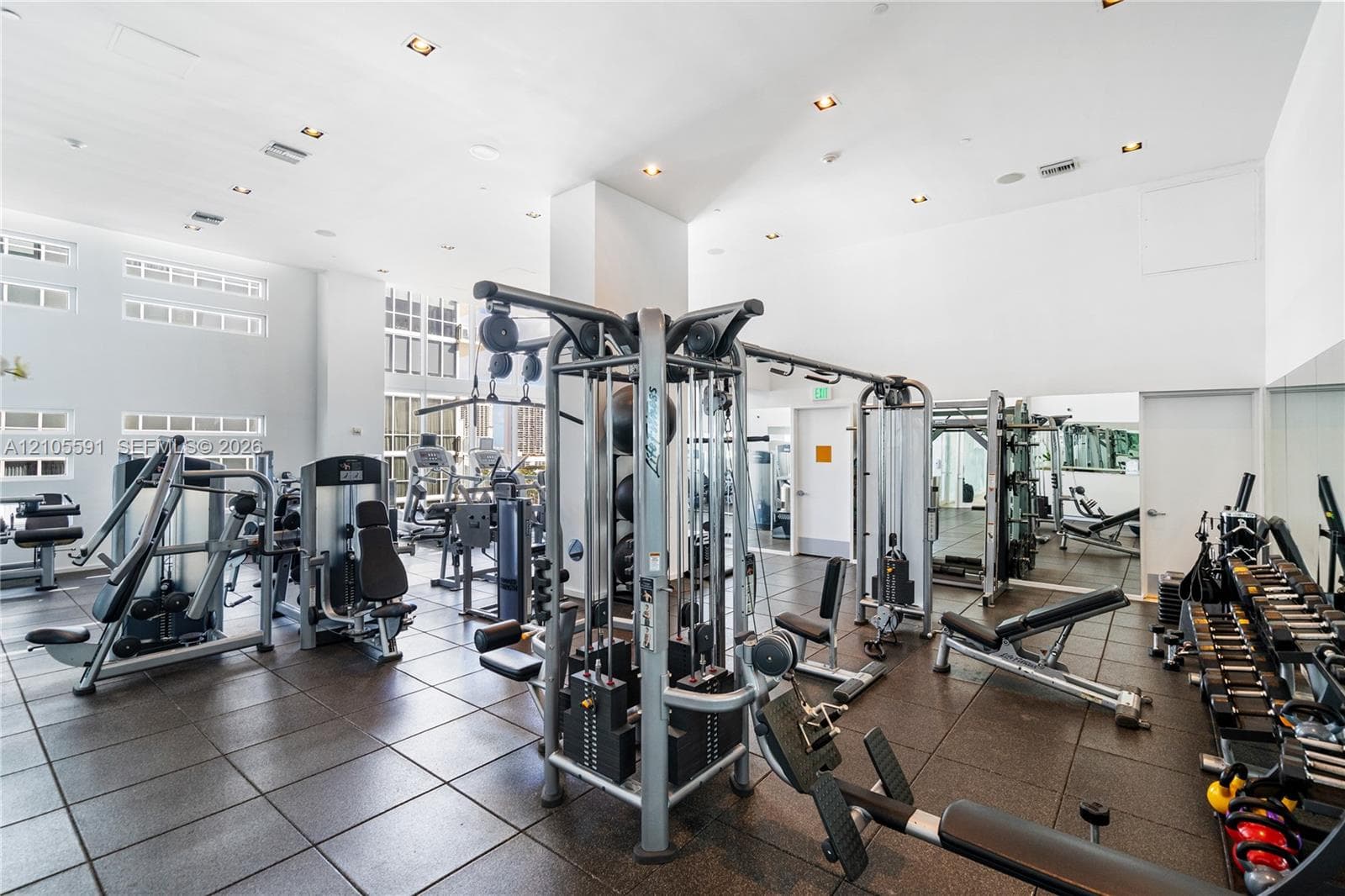 Spacious fitness area featuring rubber tile flooring, recessed lighting, and large windows