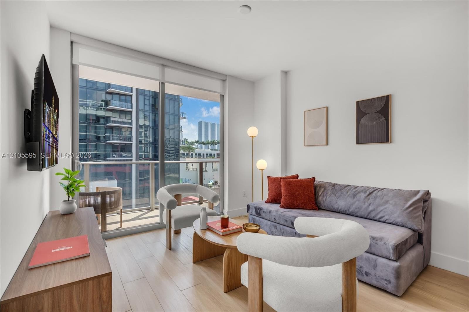 Floor-to-ceiling glass sliding doors, private balcony with metal railing, and wood-finish flooring