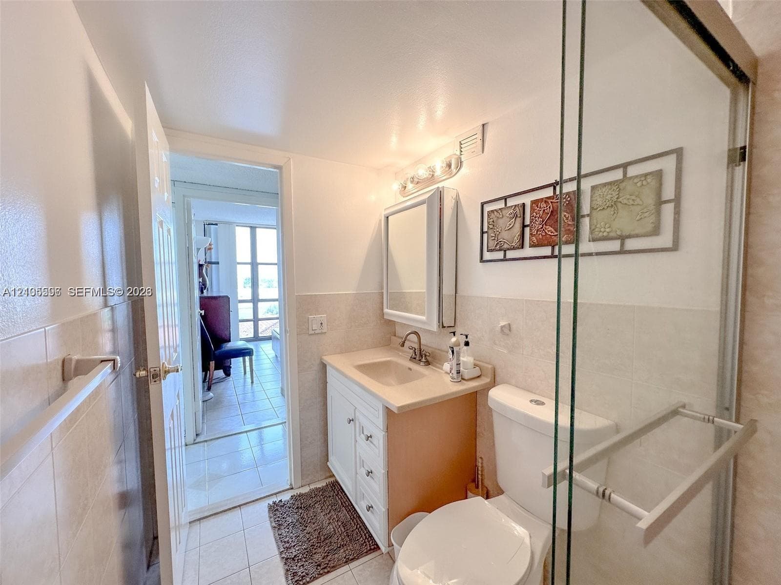 Bathroom featuring a vanity with integrated sink, glass-enclosed shower, mirrored medicine cabinet, and ceramic tile flooring