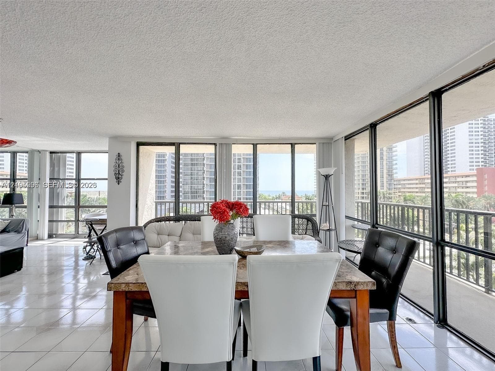 Expansive sunroom featuring floor-to-ceiling windows, polished tile flooring, and integrated black metal railings