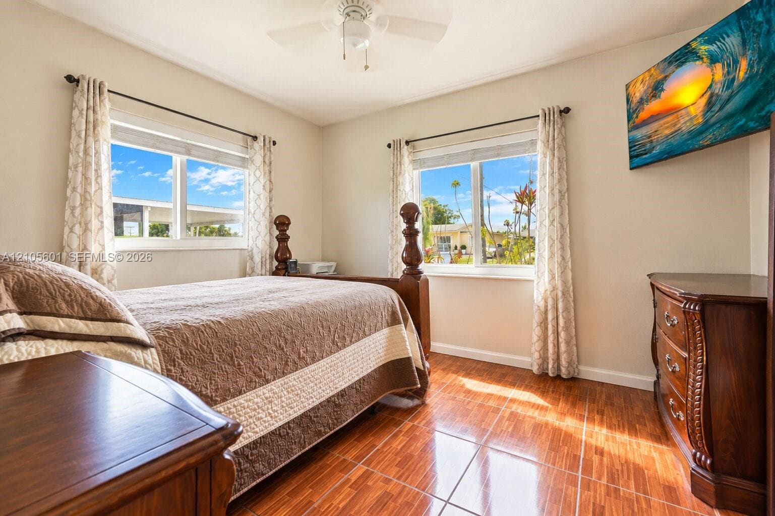 Wood-finish tile flooring, dual windows with white frames, and a ceiling fan with integrated lighting