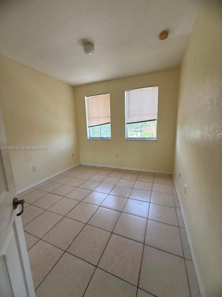 Room with neutral wall finish, large-format tile flooring, and two dual-pane windows