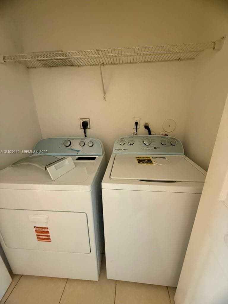 Dedicated laundry area featuring tile flooring, built-in wire shelving, and washer and dryer hookups