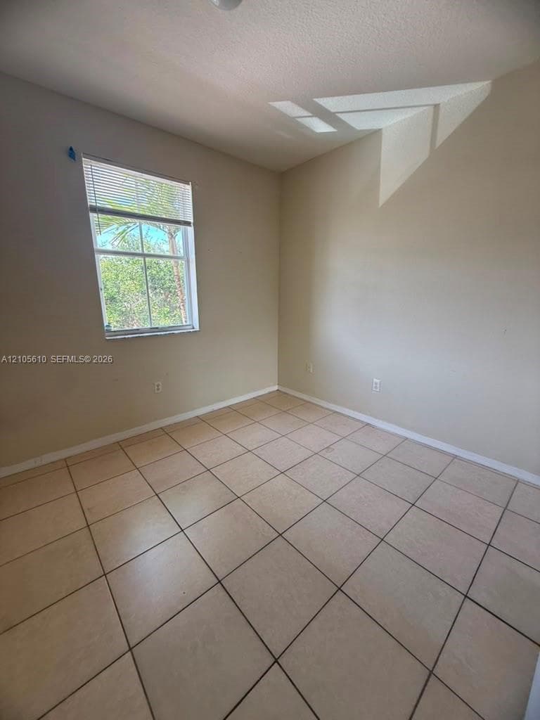 Room featuring neutral wall paint, tile flooring, and a single-pane window with blinds