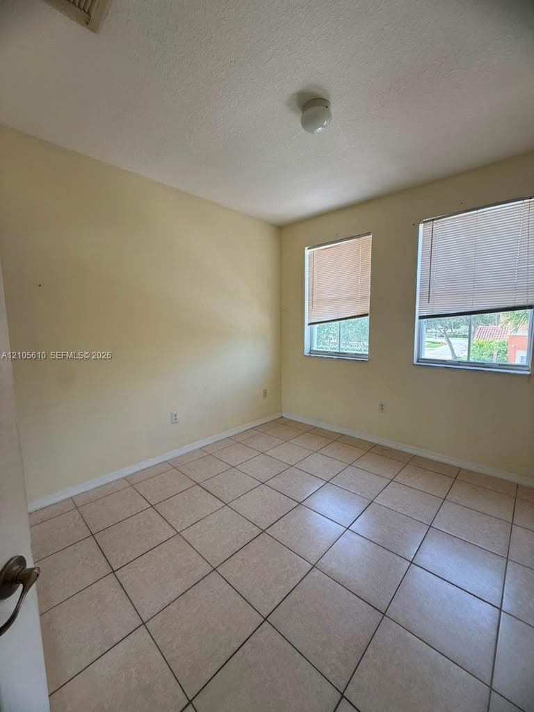 Neutral wall tones, ceramic tile flooring, and two windows with horizontal blinds
