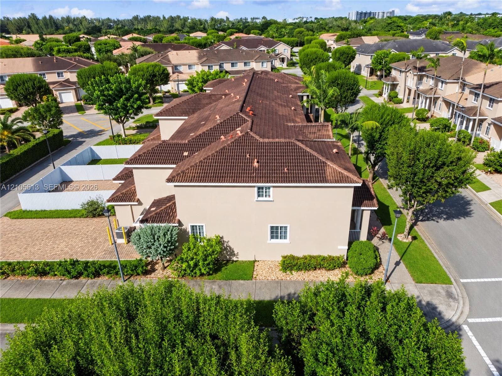 Multi-story residence featuring a tiled hip roof, exterior stucco finish, and an enclosed courtyard area with paver hardscaping