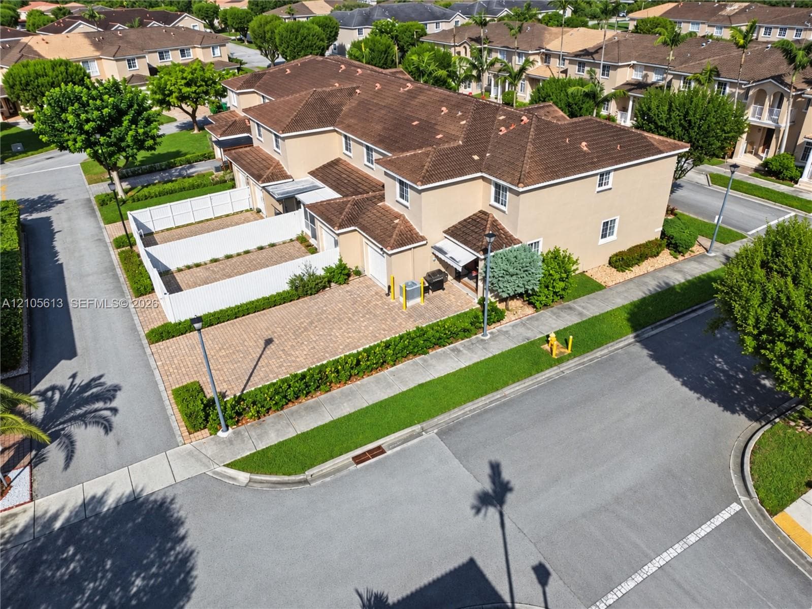 Multi-level residence featuring a textured tile roof, stucco exterior, paver driveway, and a private enclosed courtyard area