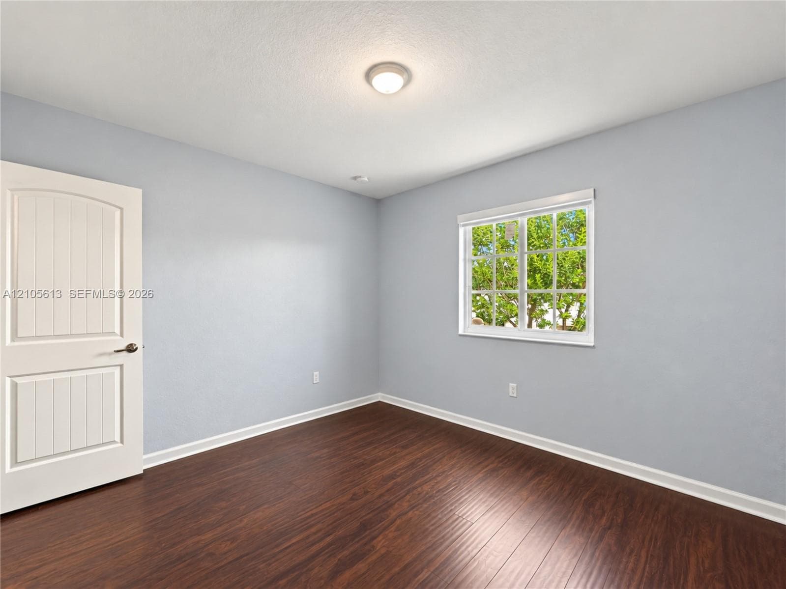 Interior space featuring wood-finish flooring, a multi-pane window, and a two-panel interior door