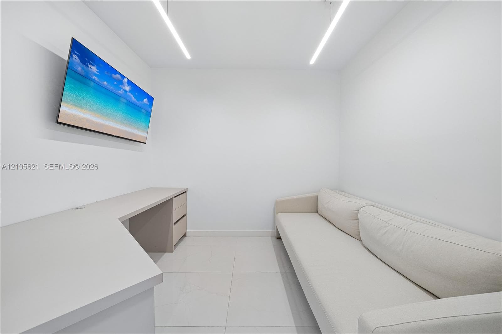 Built-in L-shaped desk with integrated storage drawers, neutral tile flooring, and linear LED ceiling lighting