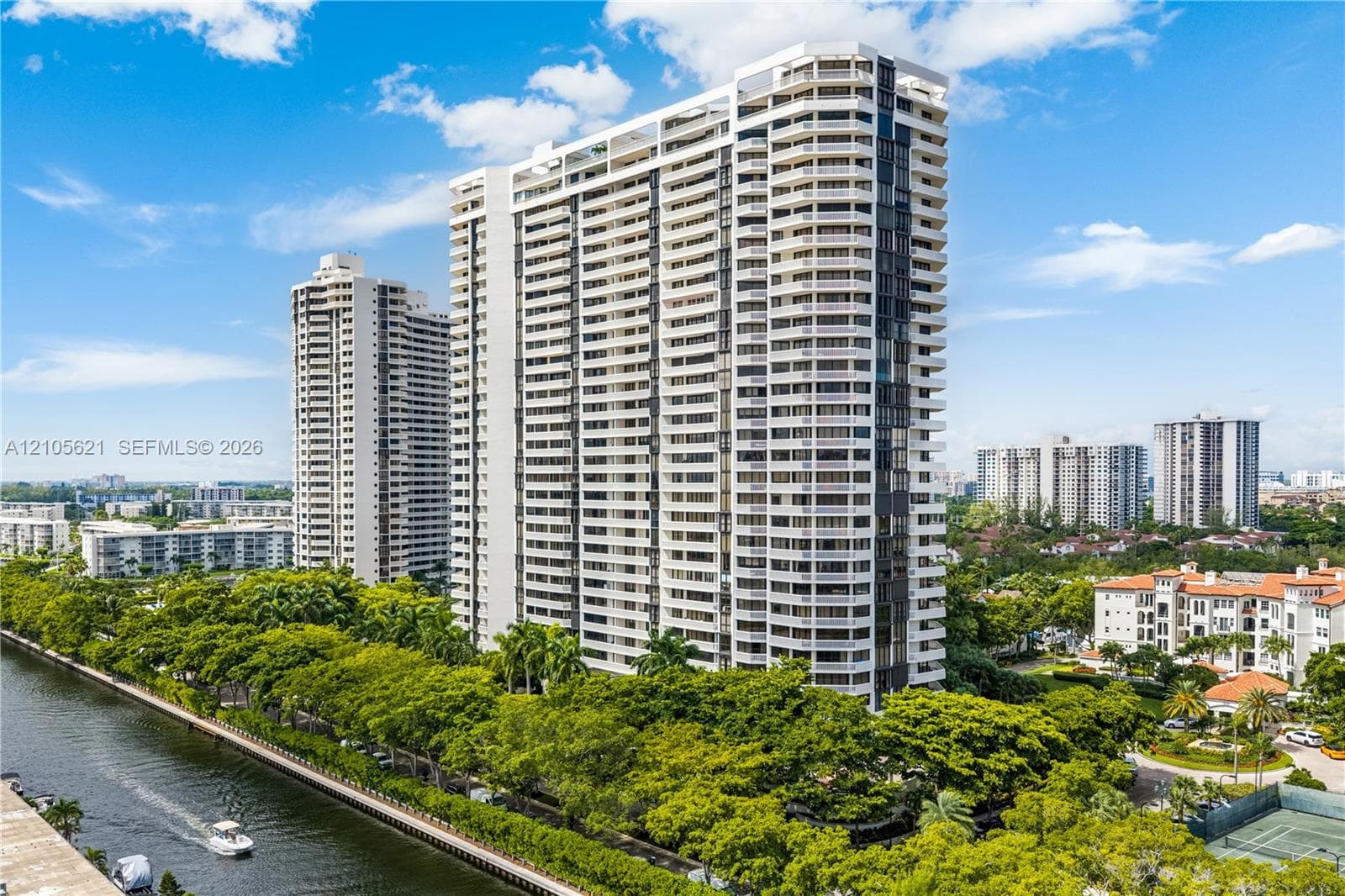 High-rise residential tower featuring private wrap-around balconies, a concrete facade, and proximity to a canal