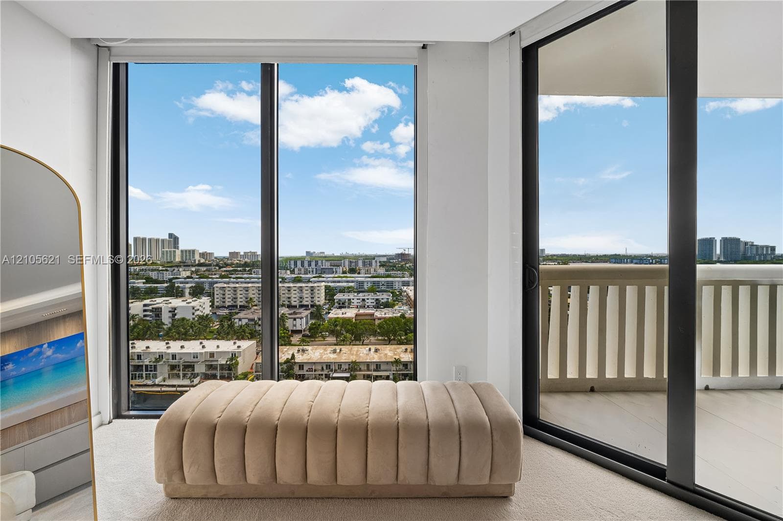 Floor-to-ceiling windows, sliding glass door leading to a balcony, and neutral carpeting