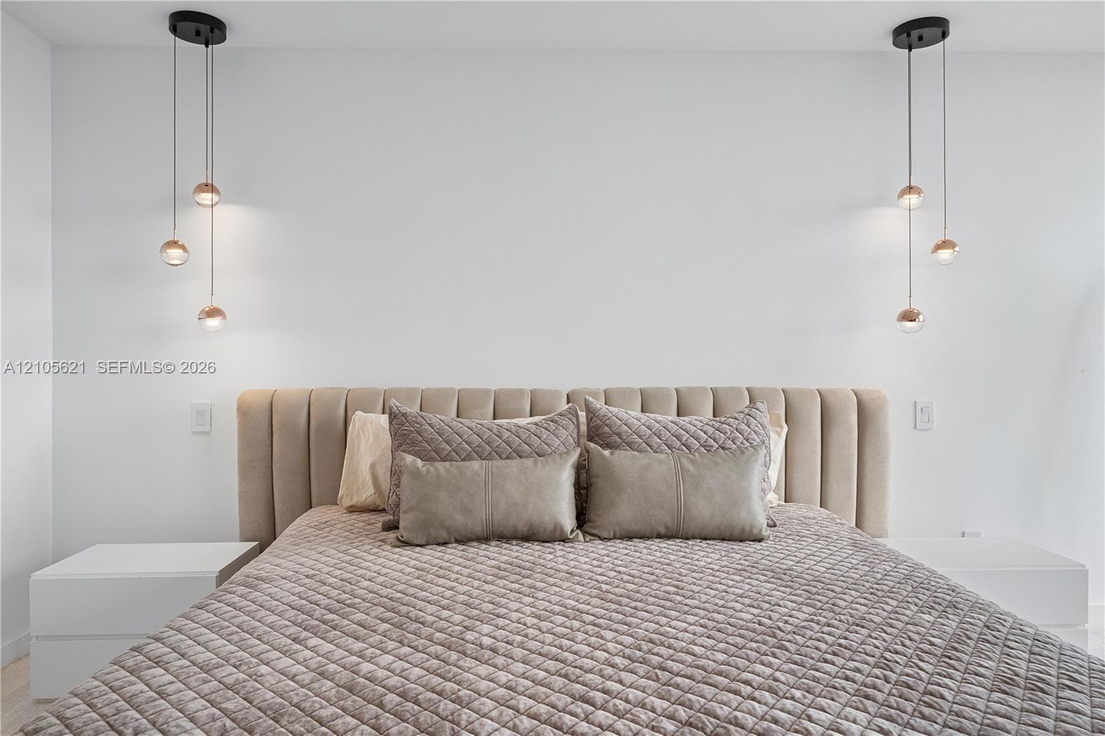 Dual multi-light globe pendant fixtures with matte black hardware and minimalist floating white bedside surfaces