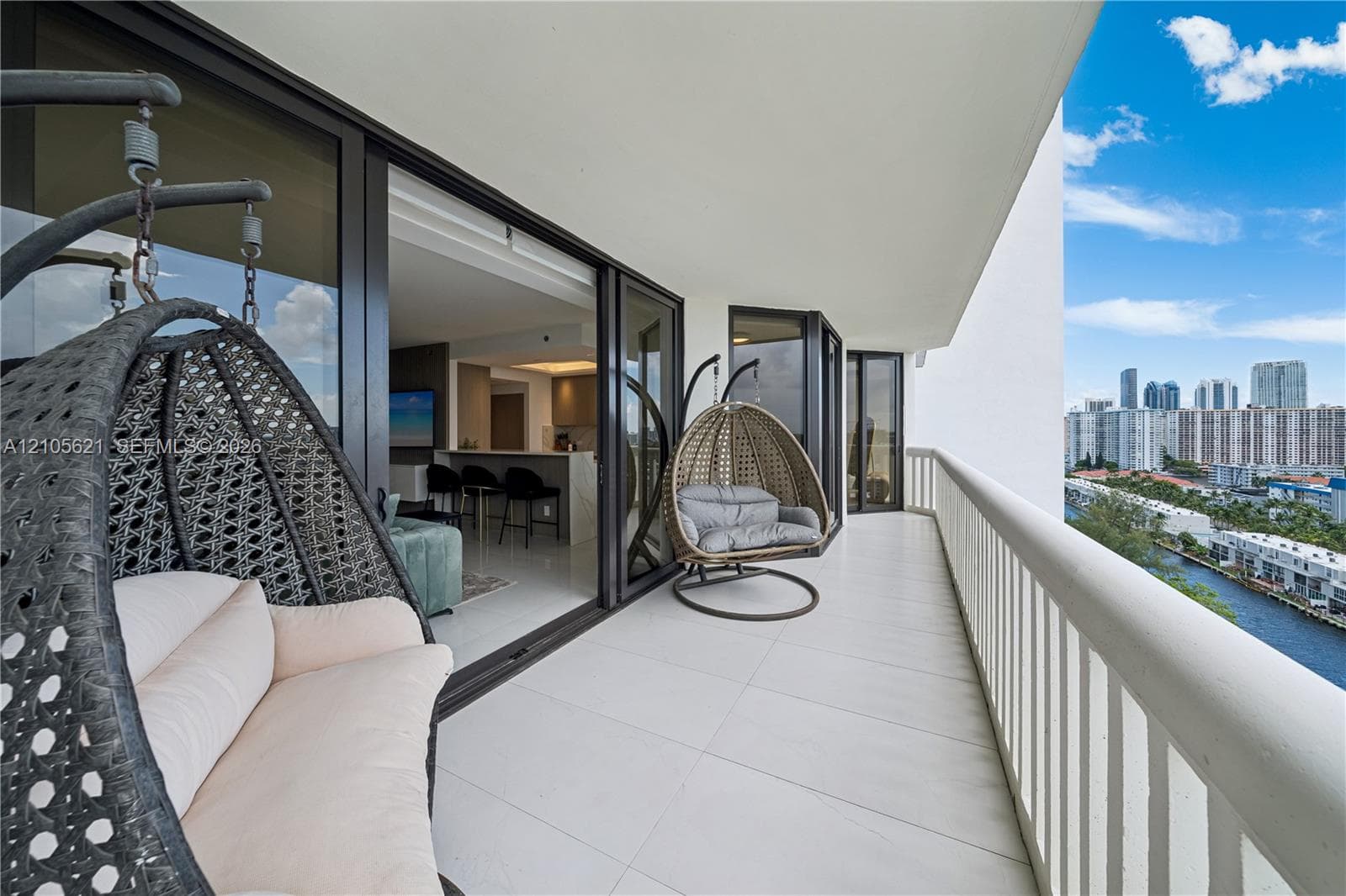 Expansive covered balcony featuring large-format tile flooring, a white metal railing, and floor-to-ceiling multi-panel sliding glass doors