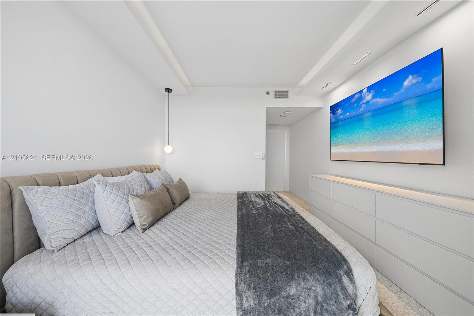 Tray ceiling with integrated recessed lighting, custom floor-to-ceiling built-in cabinetry, and modern pendant lighting