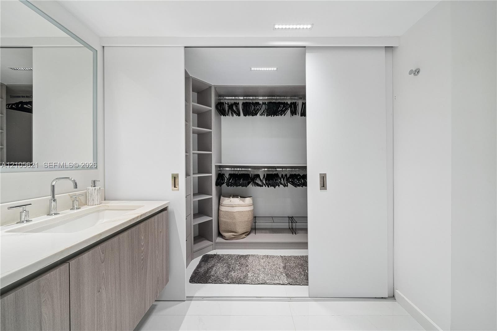 Vanity featuring a light wood-finish cabinet, stone-surface countertop, and rectangular undermount sink with a polished metal faucet