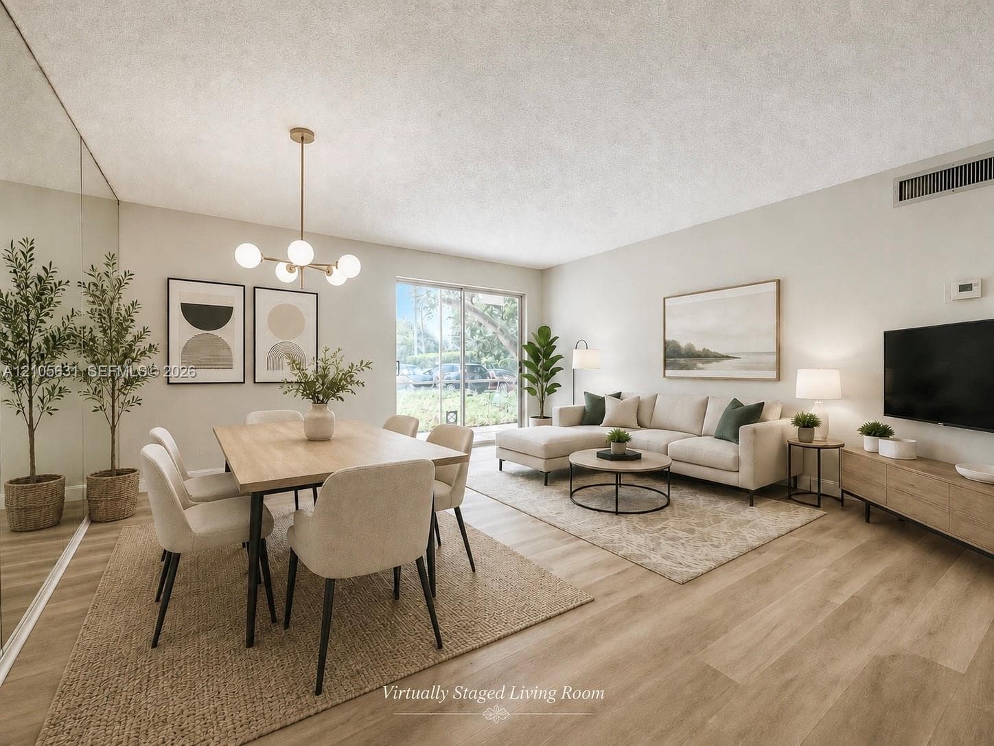Open-concept living space featuring wood-finish flooring, a wall-to-wall mirrored accent panel, a multi-globe light fixture, and a sliding glass door