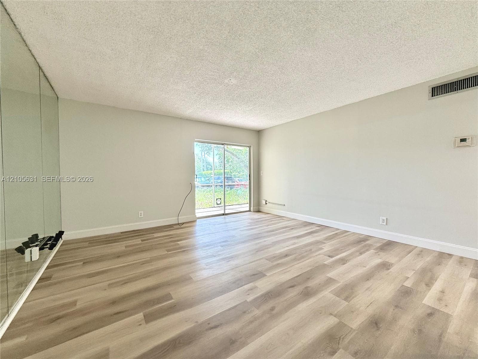 Living space featuring wood-finish flooring, floor-to-ceiling mirrored walls, and sliding glass doors