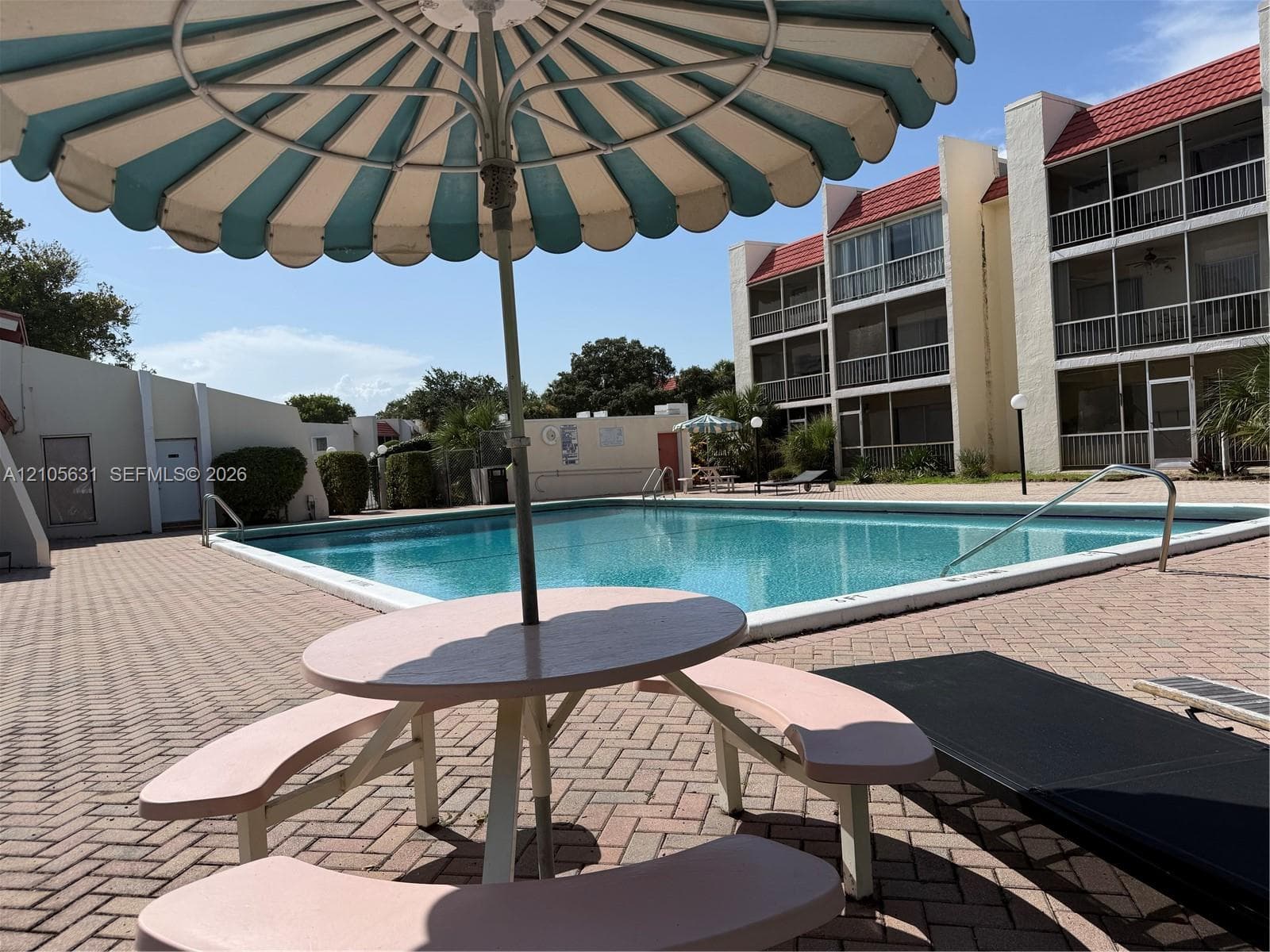 Community pool featuring a concrete deck with brick-paver surfacing and multi-story structures with balconies