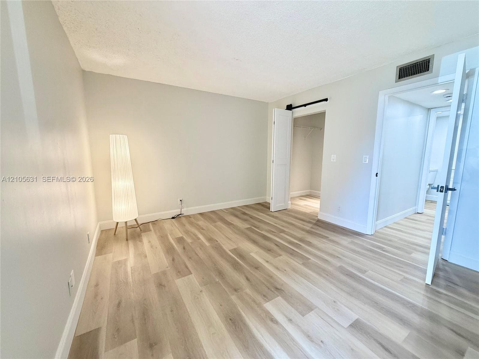 Room featuring wood-finish flooring, a sliding barn door, and a built-in closet