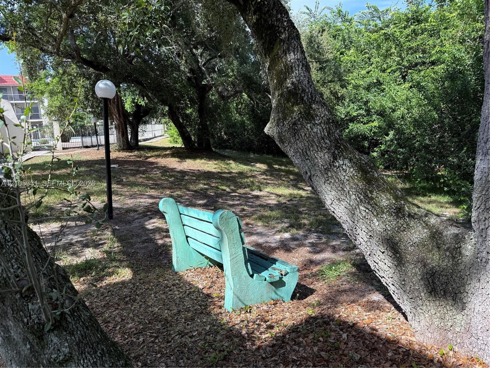 Outdoor grounds featuring mature trees, a permanent stone bench, and a standalone post-mounted globe light