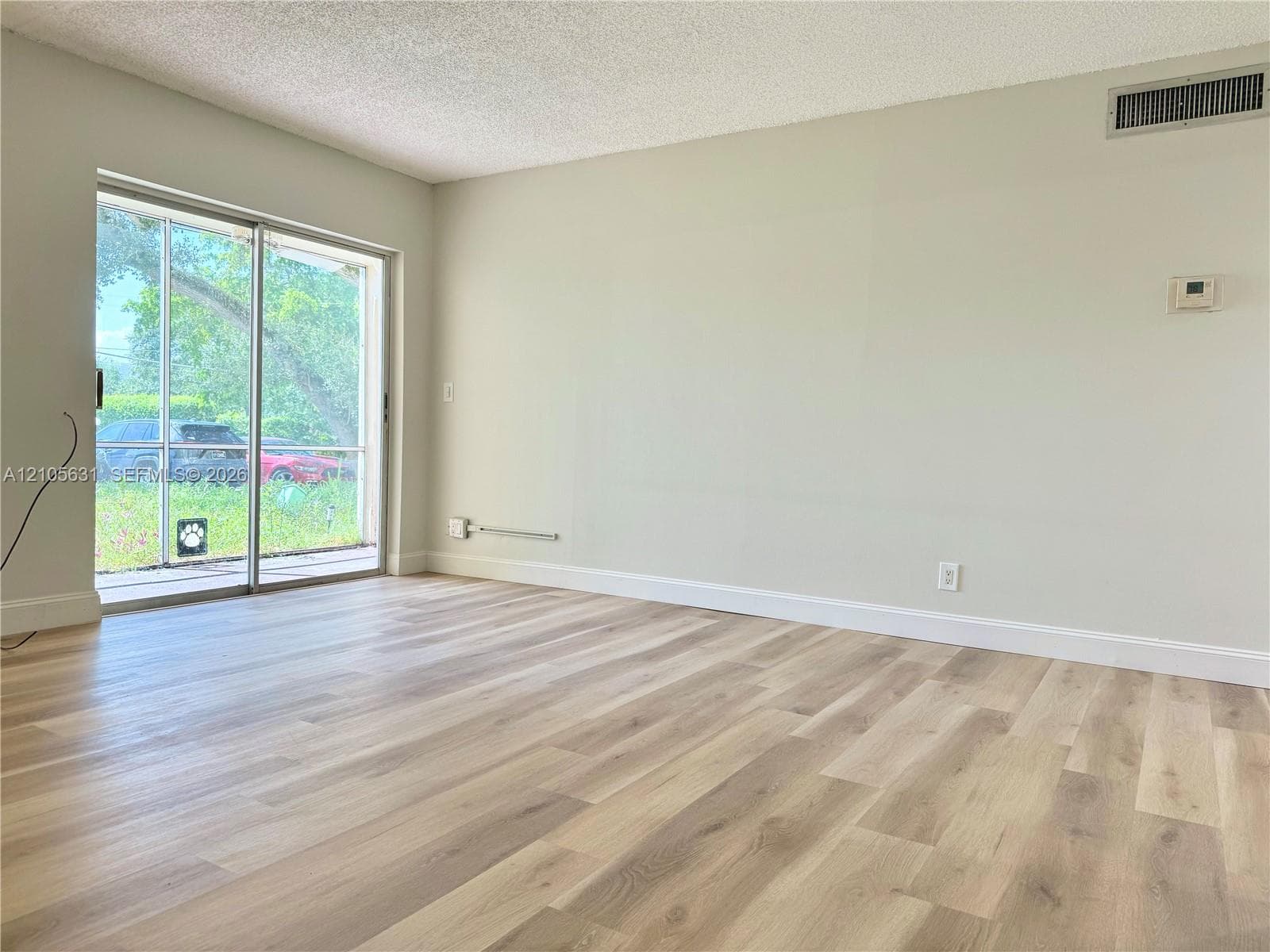 Interior room featuring wood-finish flooring, textured ceiling, and sliding glass door