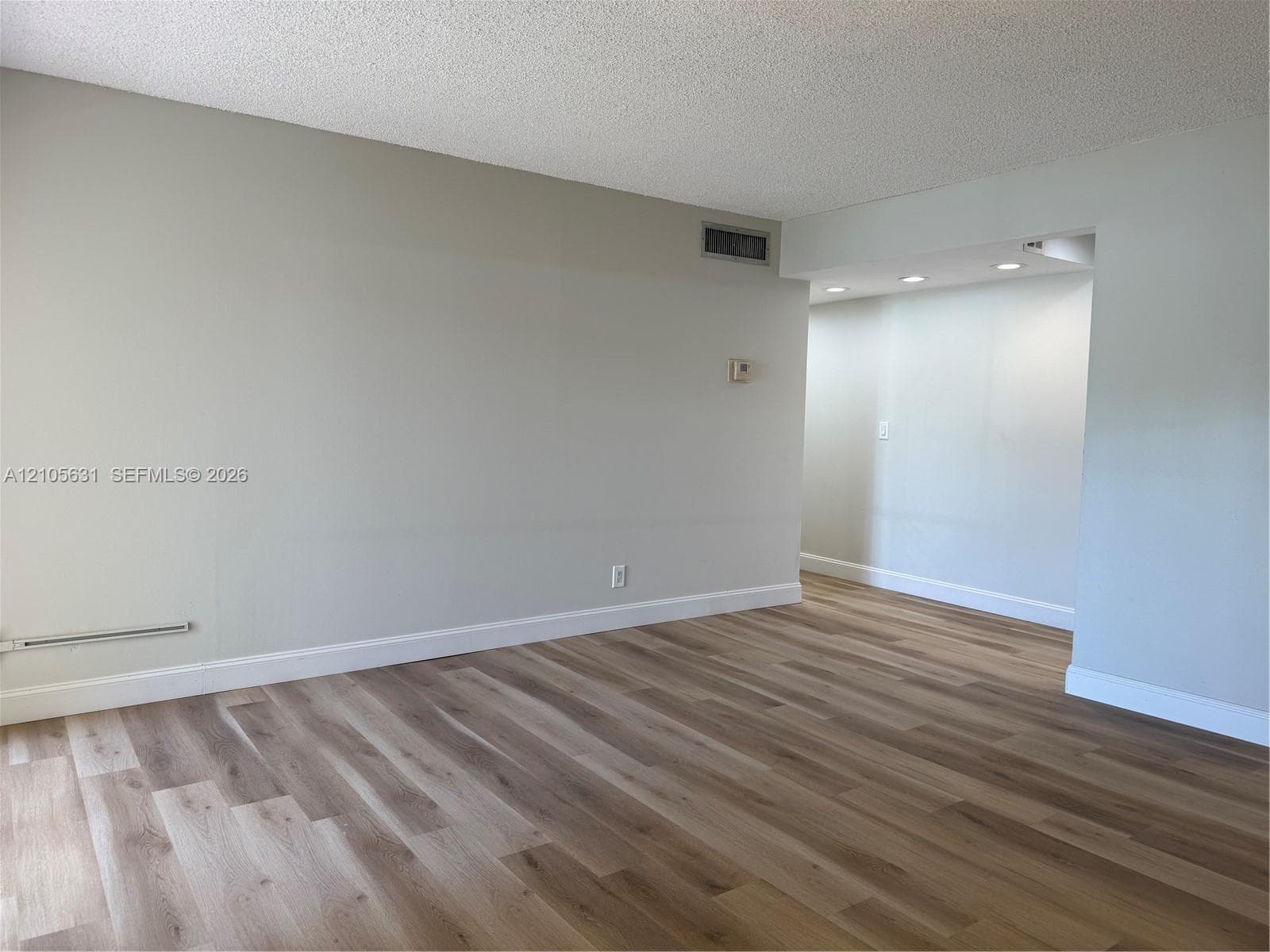 Neutral-toned walls paired with wood-finish flooring and recessed ceiling lighting