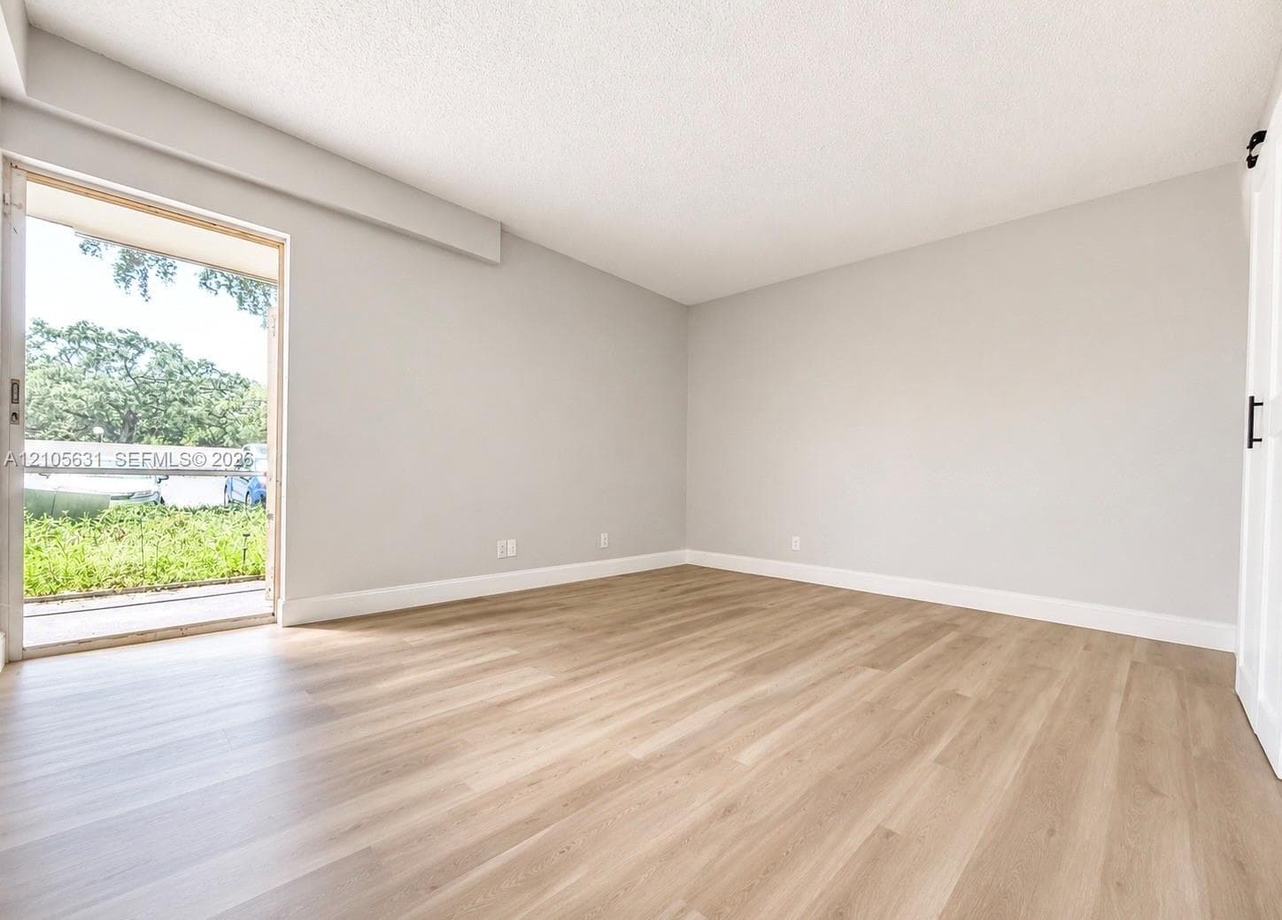 Neutral-toned interior featuring wood-finish flooring, sliding glass door, and a white interior barn door