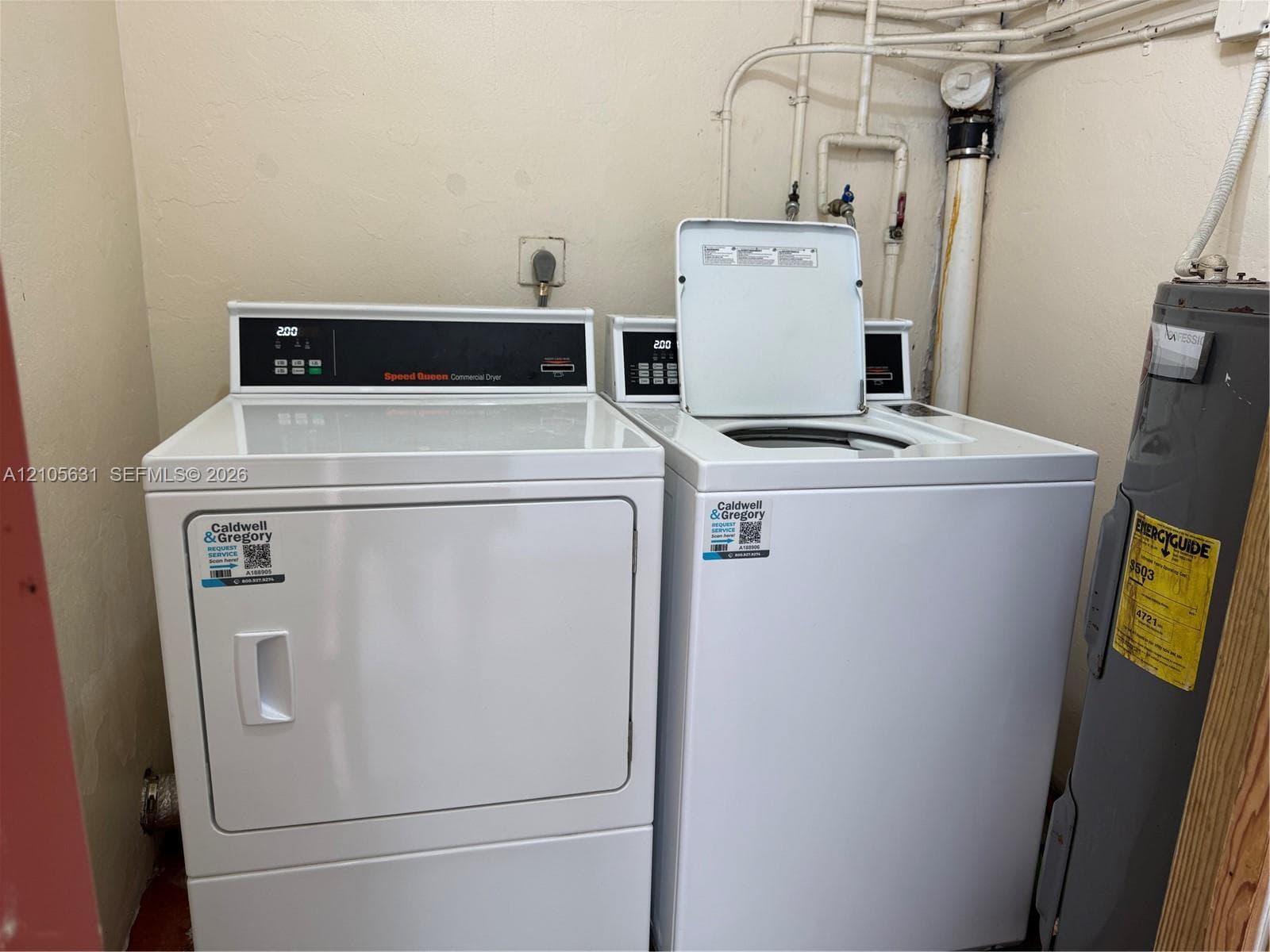 Dedicated laundry area featuring a white top-load washer, a front-load dryer, and an integrated water heater