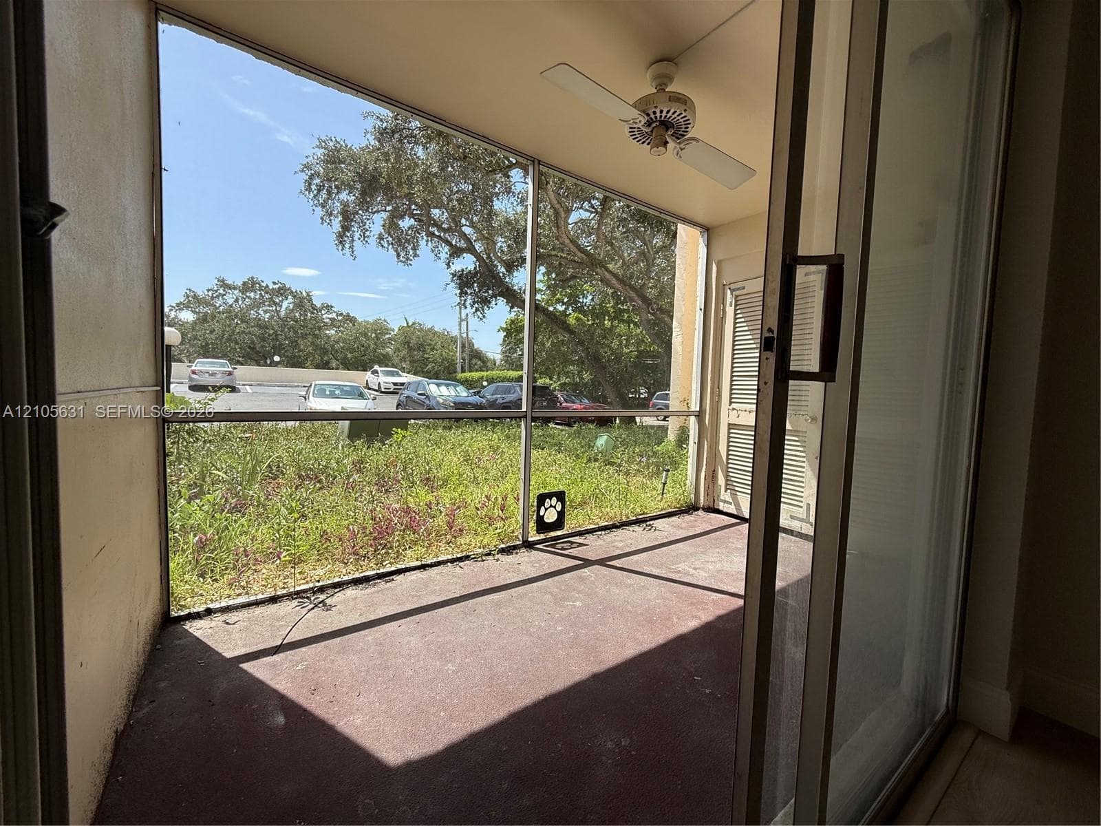 Screened-in patio featuring a ceiling fan, sliding glass door, and solid flooring