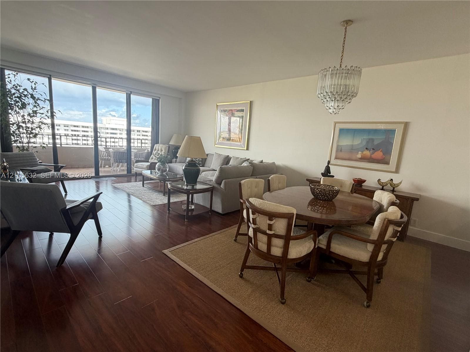Open floor plan featuring wood-finish flooring, floor-to-ceiling glass sliding doors, and a crystal tiered chandelier