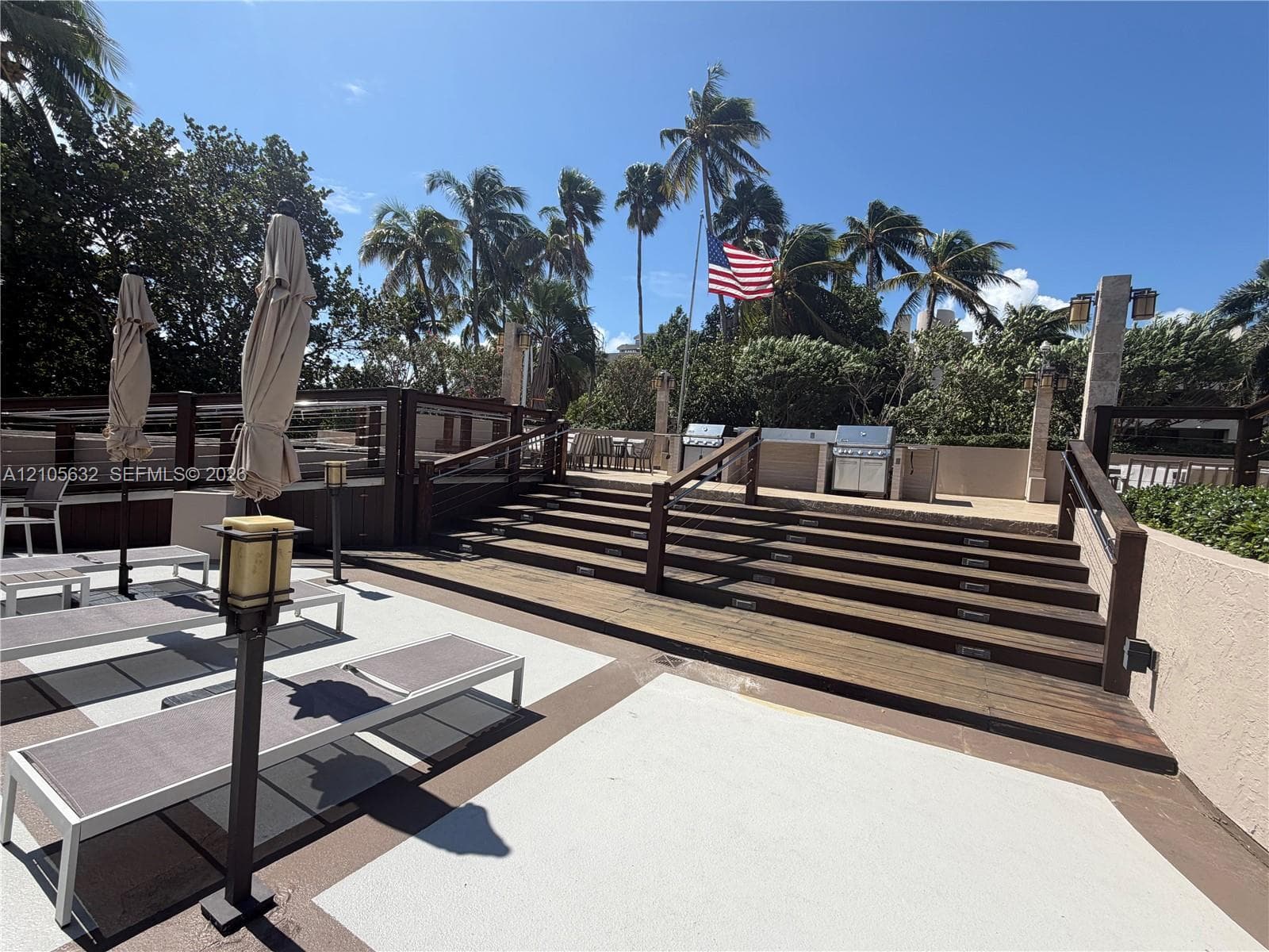 Outdoor deck featuring multi-level wood-plank stairs, integrated stair lighting, built-in stainless steel grilling station, and custom railing