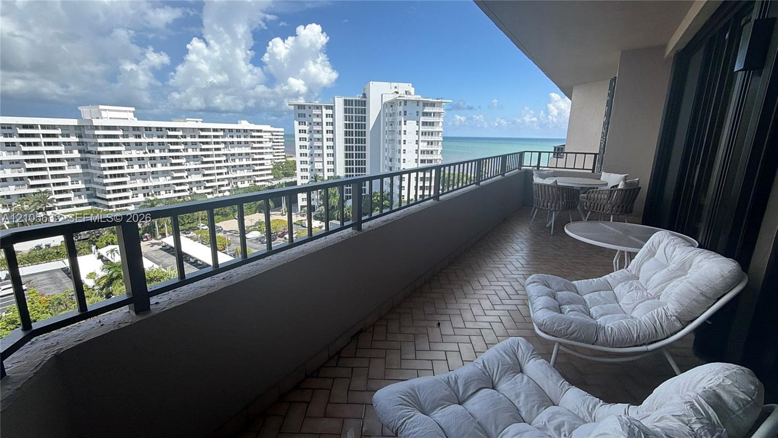 Covered balcony featuring herringbone-patterned tile flooring and metal railings