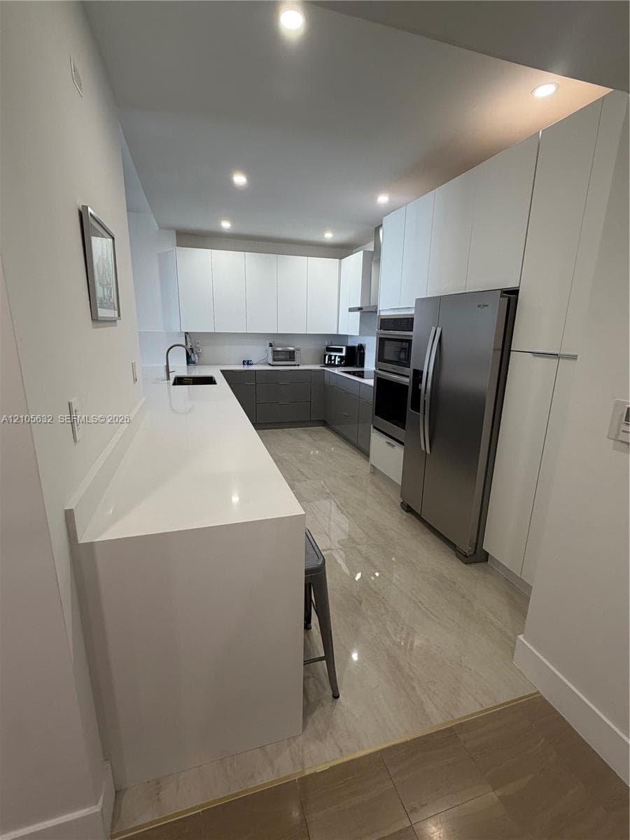 Kitchen featuring flat-panel cabinetry, stone countertops, stainless steel appliances, built-in double wall ovens, and tile flooring