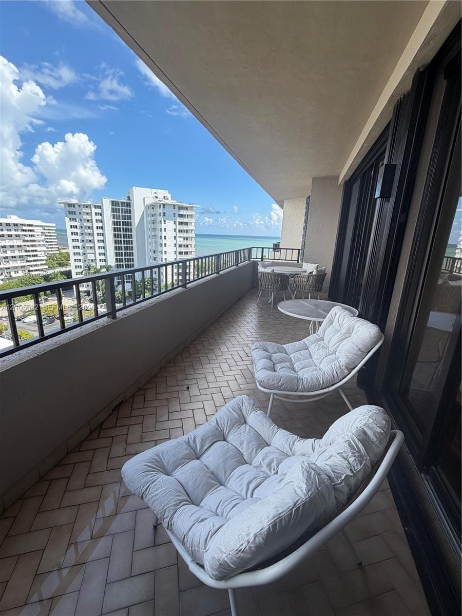 Covered balcony featuring herringbone-patterned tile flooring, metal railings, and exterior wall-mounted lighting