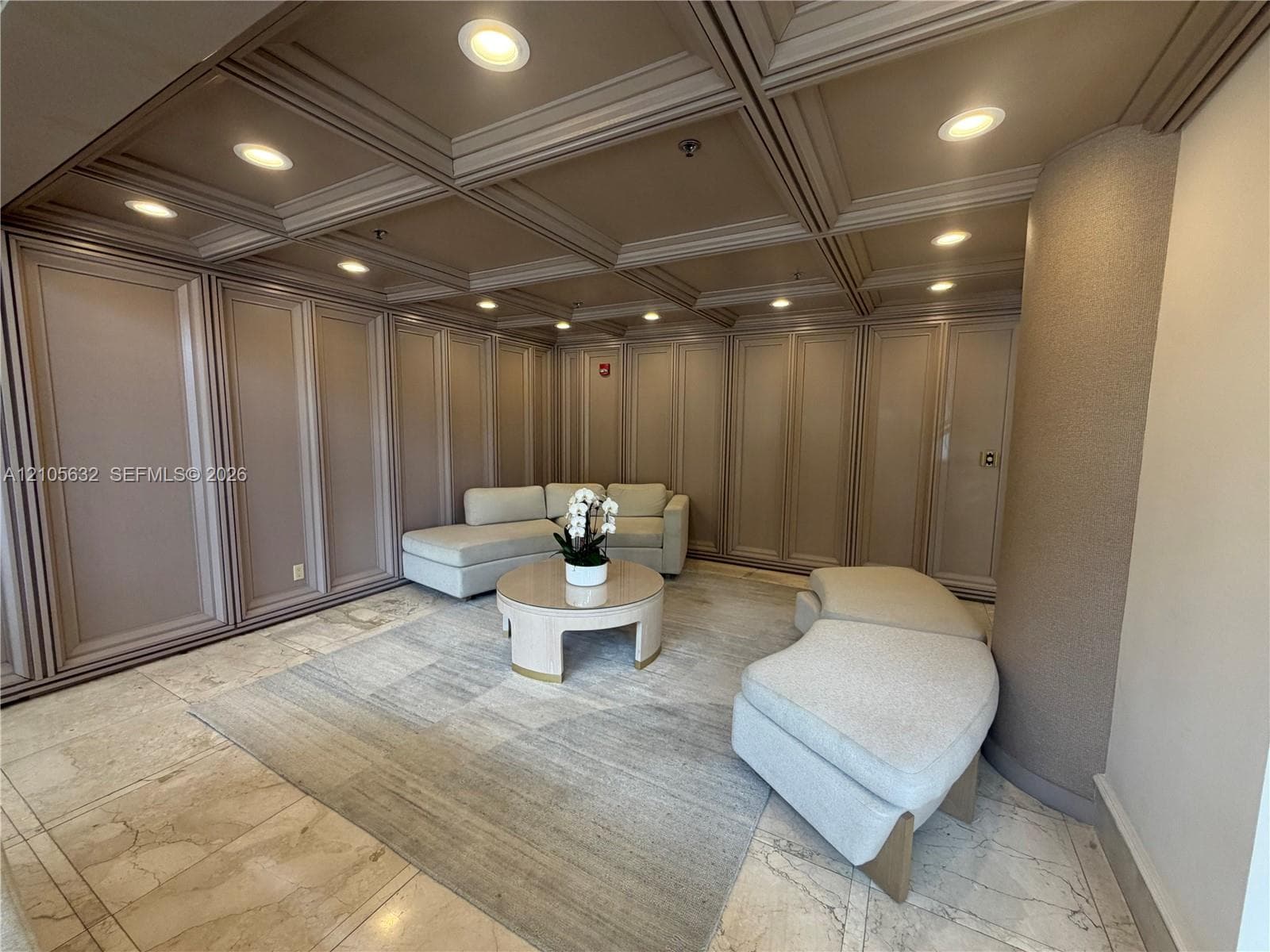 Coffered ceiling with integrated recessed lighting, stone flooring, and extensive wall paneling