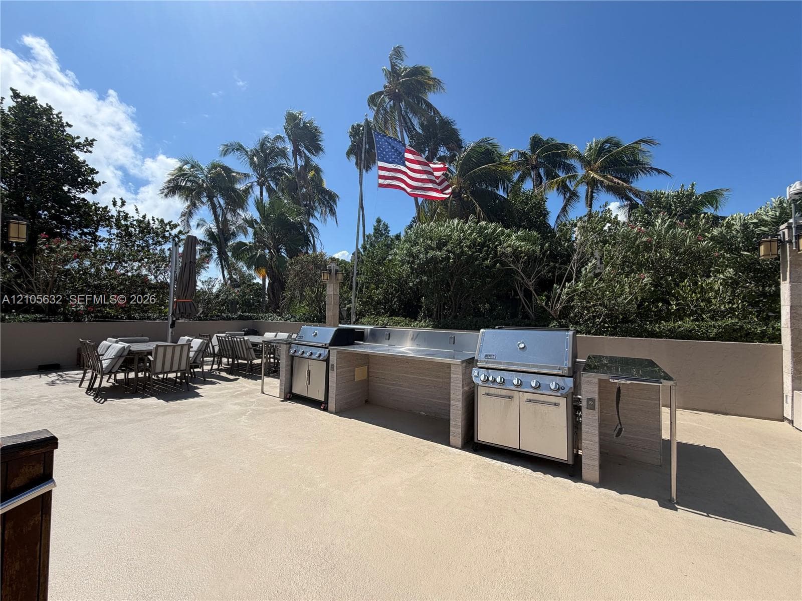Outdoor kitchen featuring dual stainless steel built-in grills, stone-finished cabinetry, stainless steel countertops, and a concrete patio surface