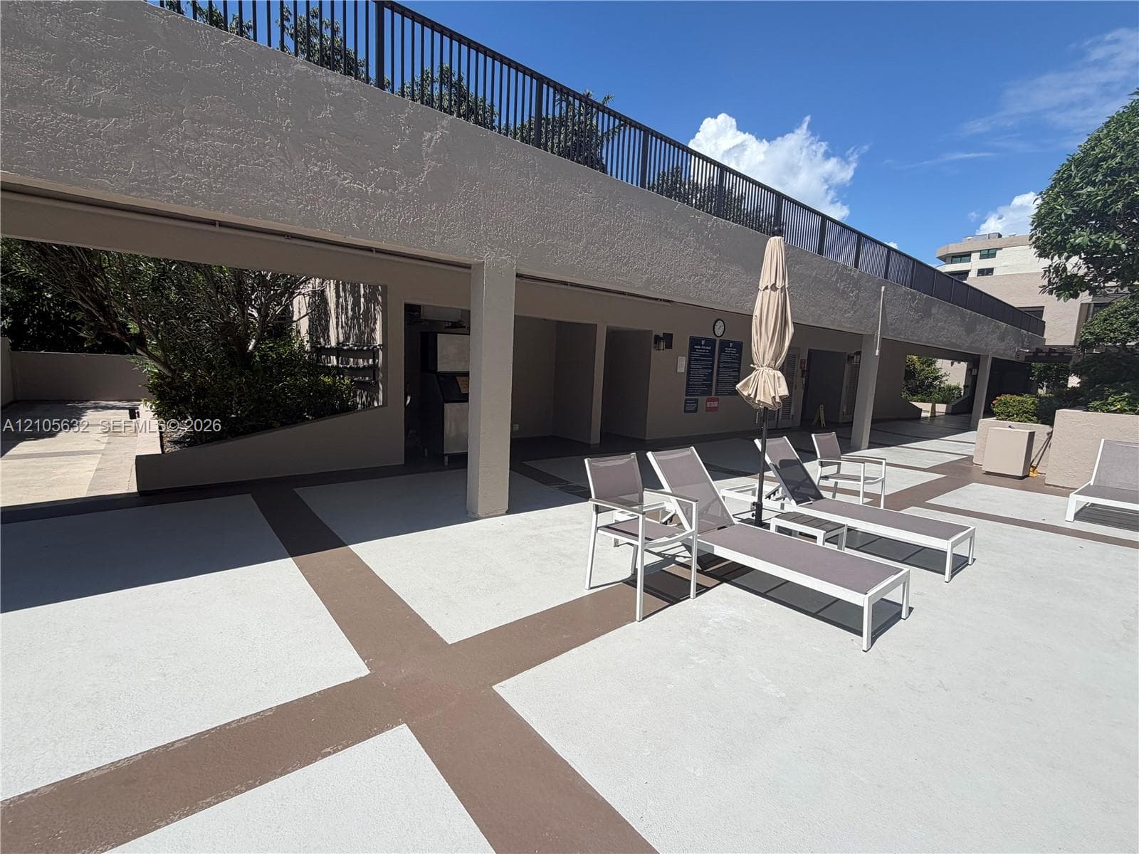 Outdoor patio featuring patterned concrete surfacing, a covered pavilion area, and a railed upper-level terrace